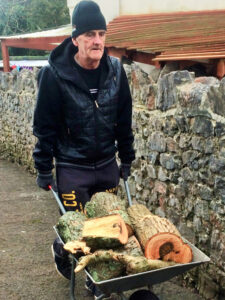 Vane Hill ARBD care home resident moving wheelbarrow full of logs for their neighbour