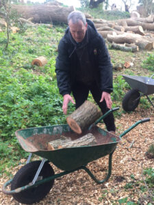 Vane Hill ARBD care home resident filling wheelbarrow with logs for their neighbour